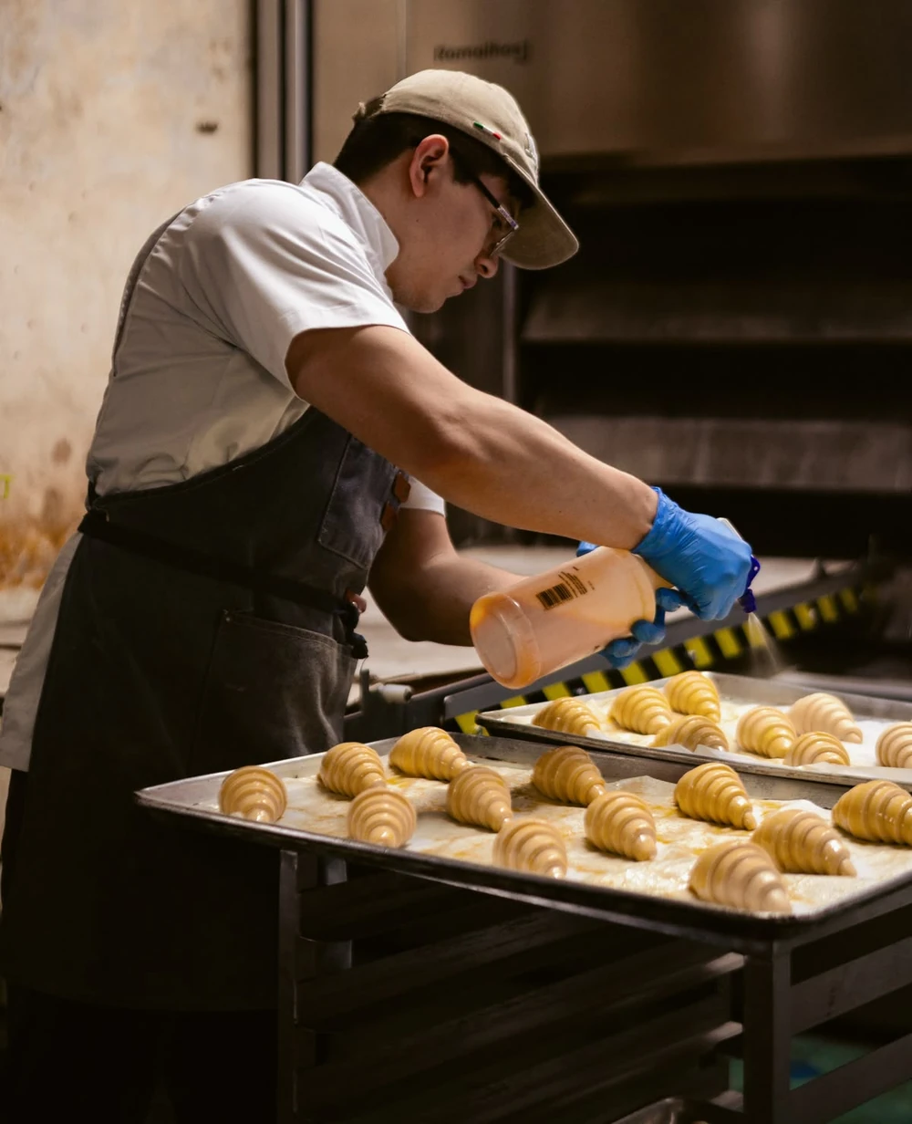 Panadero barnizando croissants con huevo